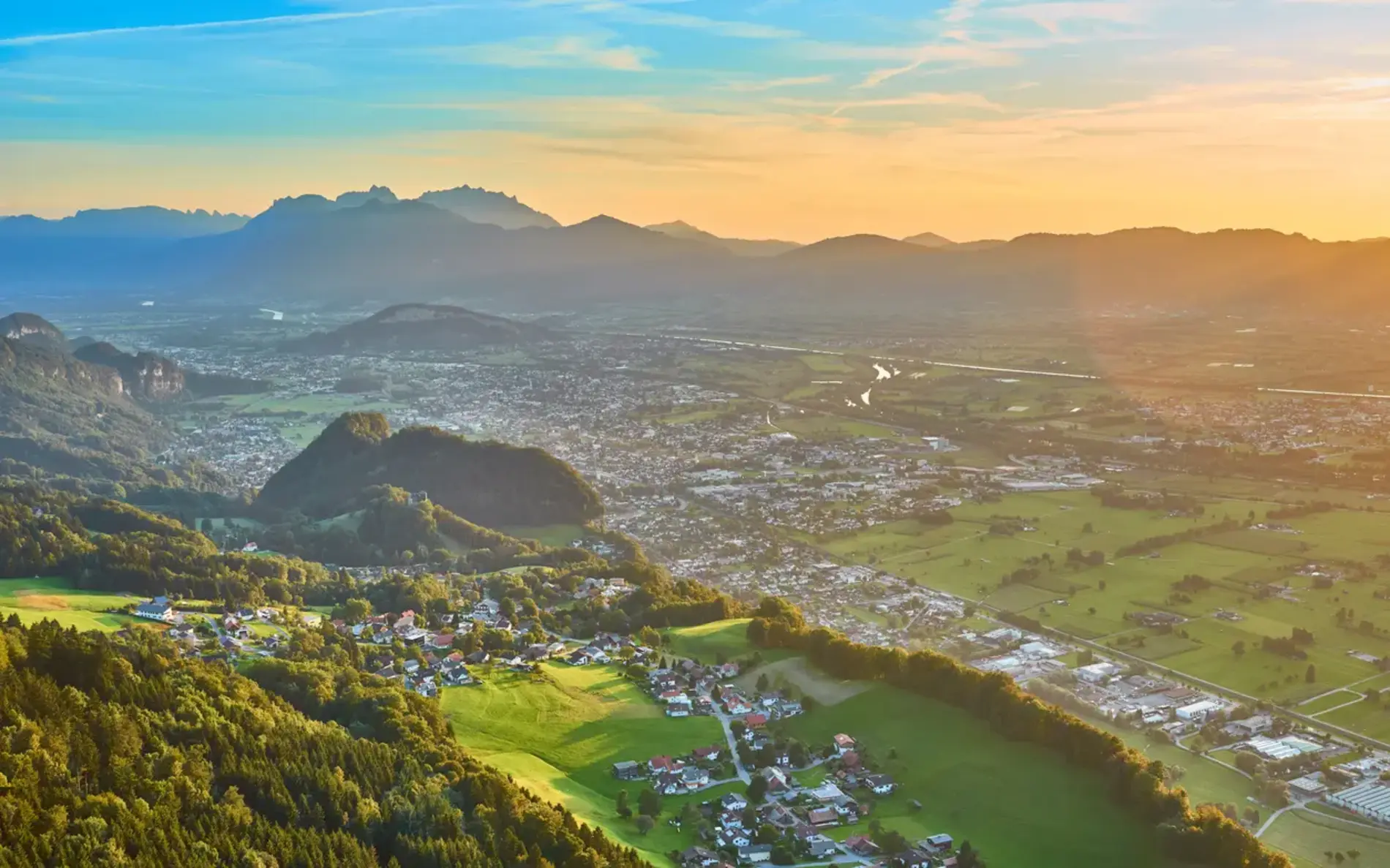 Viele kleine Häuser umgeben von Grün und Hügel. Blick von oben