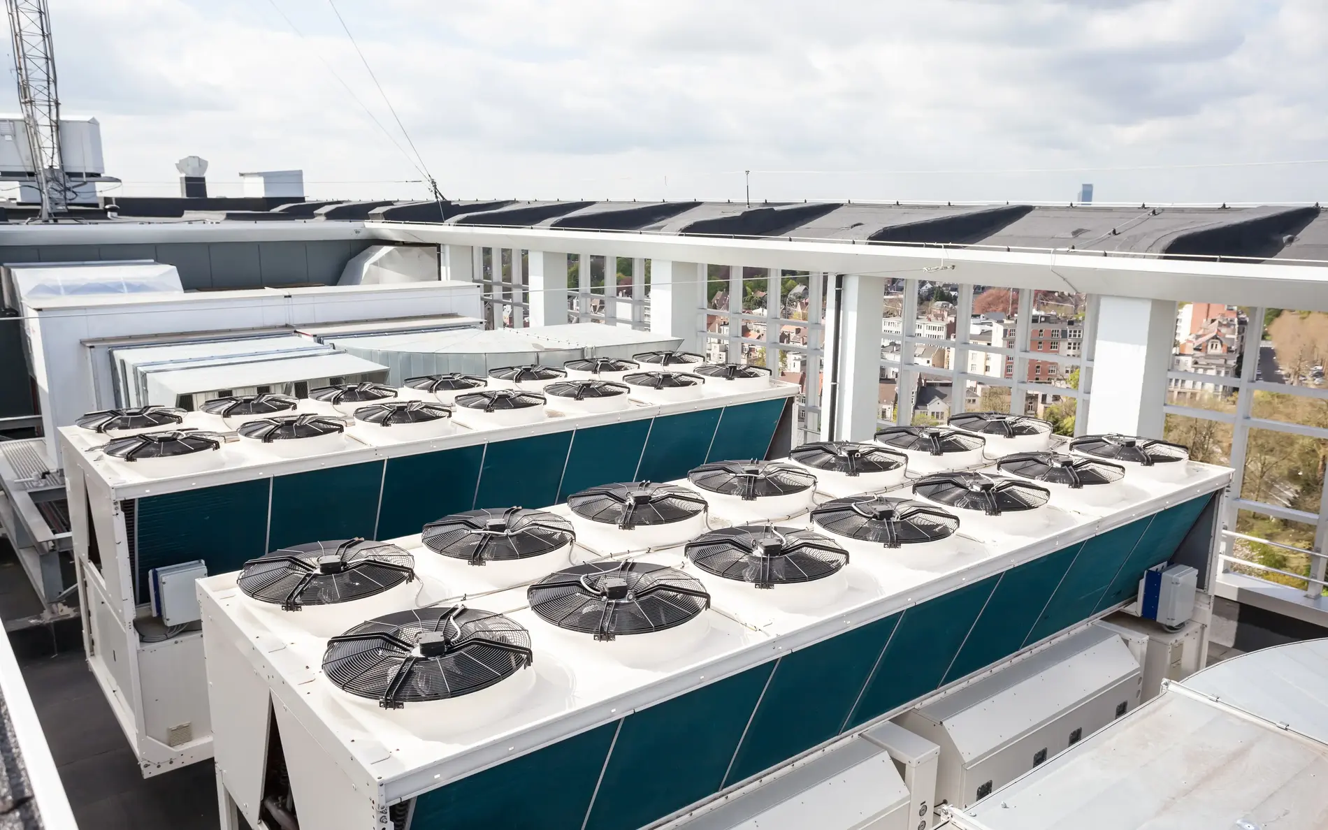 Große Kühlanlage mit vielen einzelnen Ventilatoren am Dach eines Gebäudes. Im Hintergrund sind andere Dächer zu sehen.