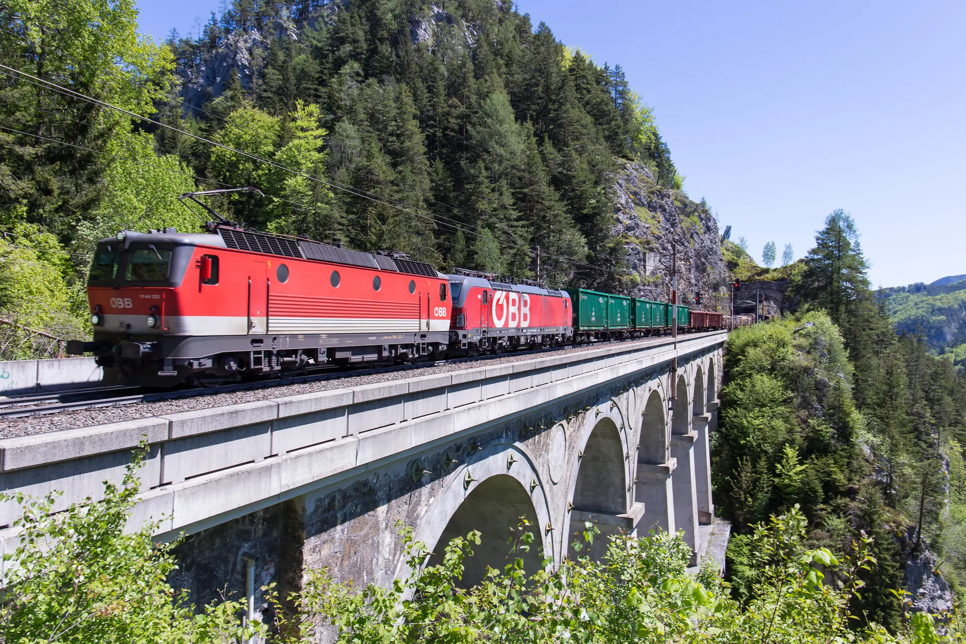 Gütertransport über die Schiene mit einem ÖBB Zug. Der Zug fährt über eine Brücke.