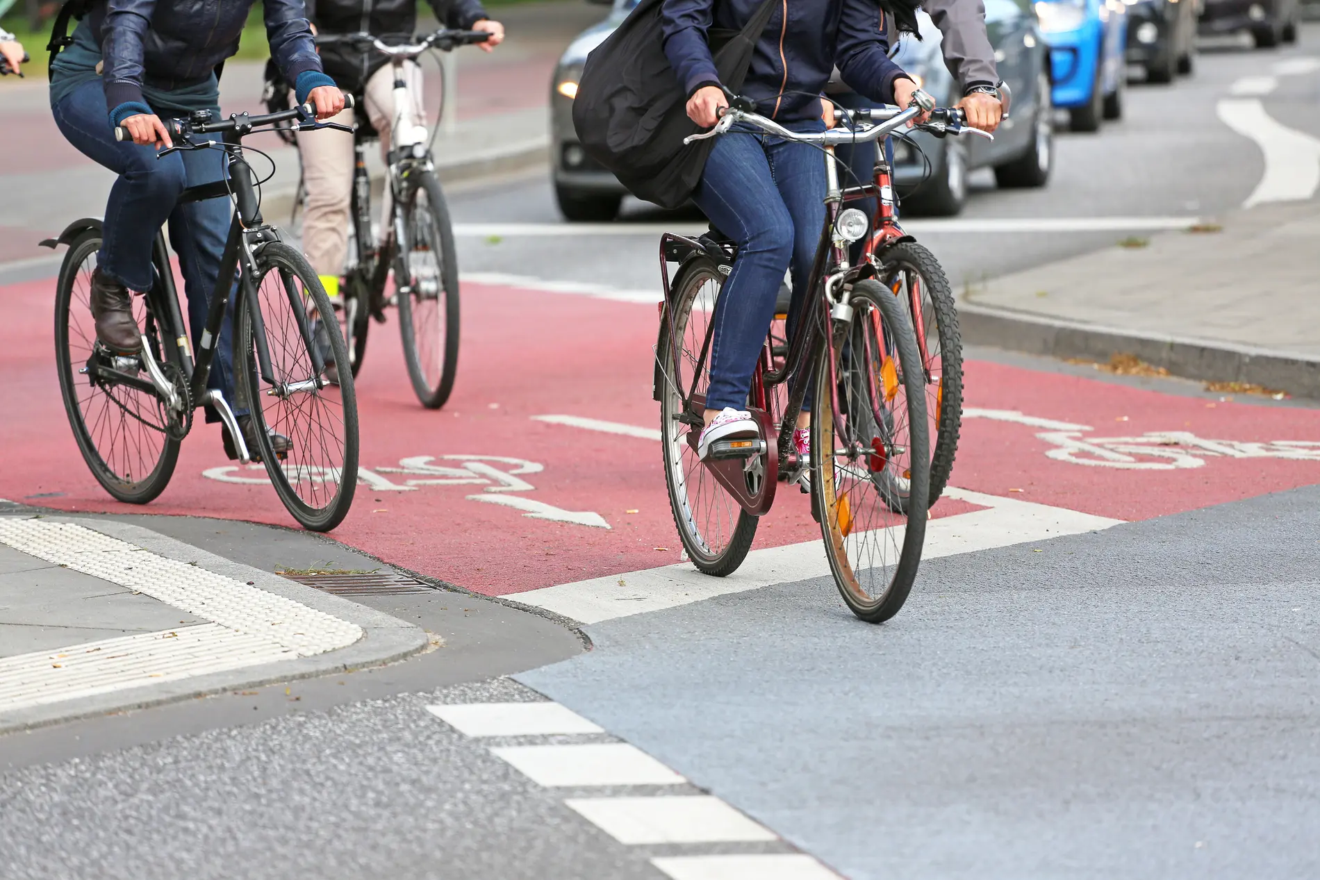 Fahrradfahrende auf rot markiertem Radweg. Der Radweg ist teilweise baulich getrennt von der Fahrbahn.