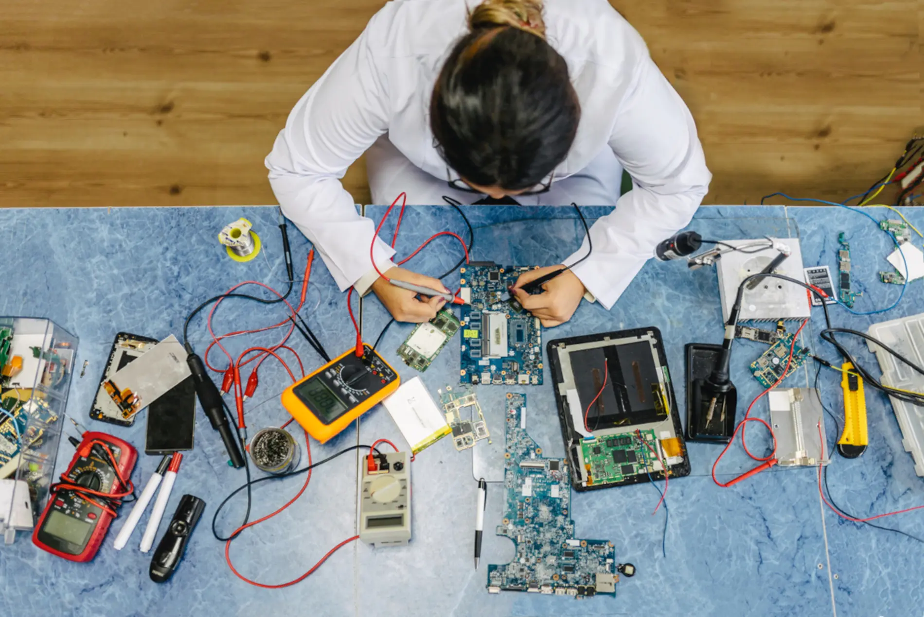 Zu sehen ist eine Frau von oben die Elektronikteile zusammenschraubt